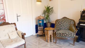 A room with a wooden chair, a small table, a potted plant, and a piano.