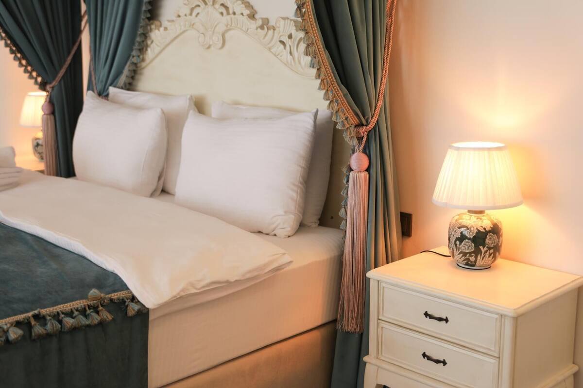 A neatly made bed with white linens, a decorative headboard, and a bedside table with a lamp.