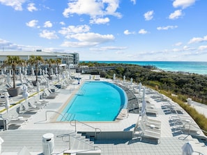 A large outdoor swimming pool with lounge chairs and umbrellas, surrounded by a landscaped area with palm trees and a view of the ocean. - Office Space | Private Pool | LSV | Firepit (Santa Rosa Beach)