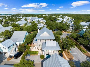 A residential area with houses featuring gabled roofs and a central house with a large front yard and a swimming pool. - Office Space | Private Pool | LSV | Firepit (Santa Rosa Beach)