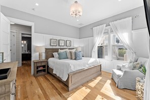 A bedroom with a wooden bed, a nightstand, a chair, and a window with curtains. - Office Space | Private Pool | LSV | Firepit (Santa Rosa Beach)
