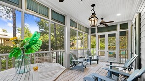 A covered outdoor area with a table, chairs, and a ceiling fan.