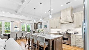 A modern kitchen with a central island, wooden cabinets, and pendant lighting.