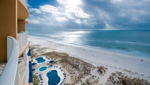 A beach view from a hotel balcony with a pool and lounge chairs. - Phoenix Gulf Towers 1106 2 Bedroom Condo (Orange Beach)