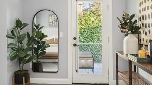 Une porte avec un panneau de verre, un miroir et deux plantes en pot.