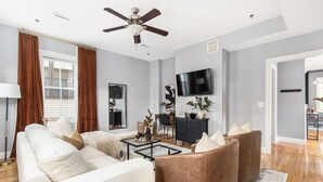 Un salon moderne avec un canapé, des fauteuils, une table basse et un téléviseur.
