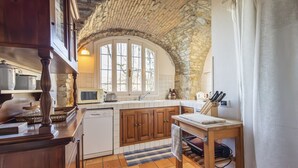 Una cocina con armarios de madera, techo de piedra y un ventanal amplio.