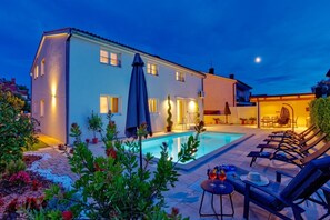A two-story house with a swimming pool, outdoor seating, and a well-lit patio area. - Villa Nata in Pula - Haus für 8 Personen (Pula)
