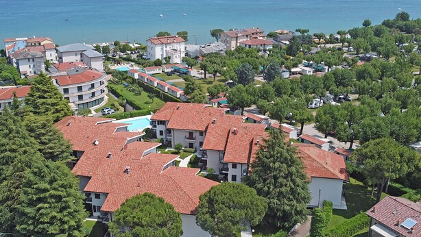 Un quartier résidentiel situé sur la côte, composé de plusieurs immeubles, dont certains sont coiffés de toits en tuiles rouges, et offrant une vue dégagée sur la mer.