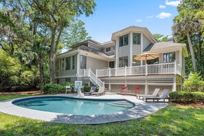 Une maison à deux étages avec une piscine, une terrasse couverte et un escalier menant à un balcon.