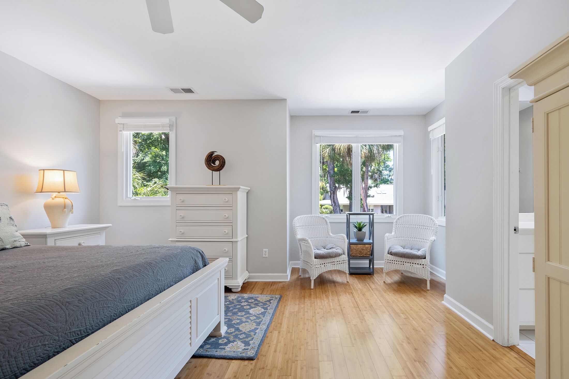 A bedroom with a bed, dresser, two chairs, a window, and a door.