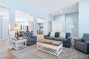 A spacious living room with a sofa, armchairs, a coffee table, and a lamp.