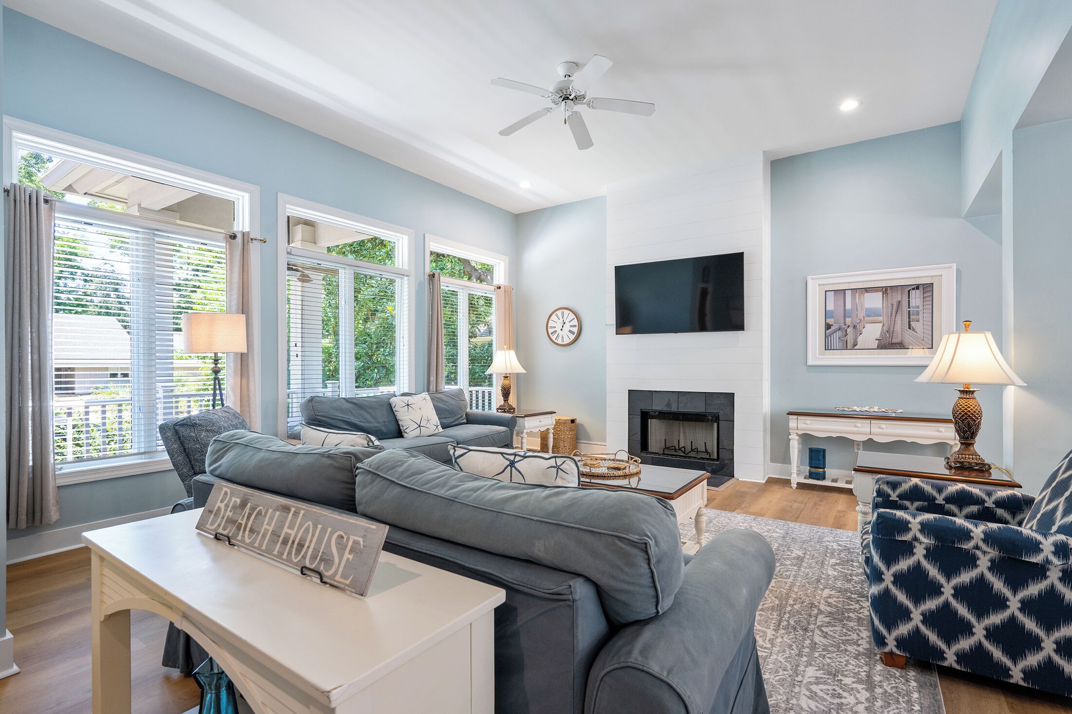 A living room with a sofa, a coffee table, a fireplace, and a television mounted on the wall.