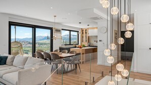 A modern living space with a dining area, kitchen, and large windows offering a mountain view.