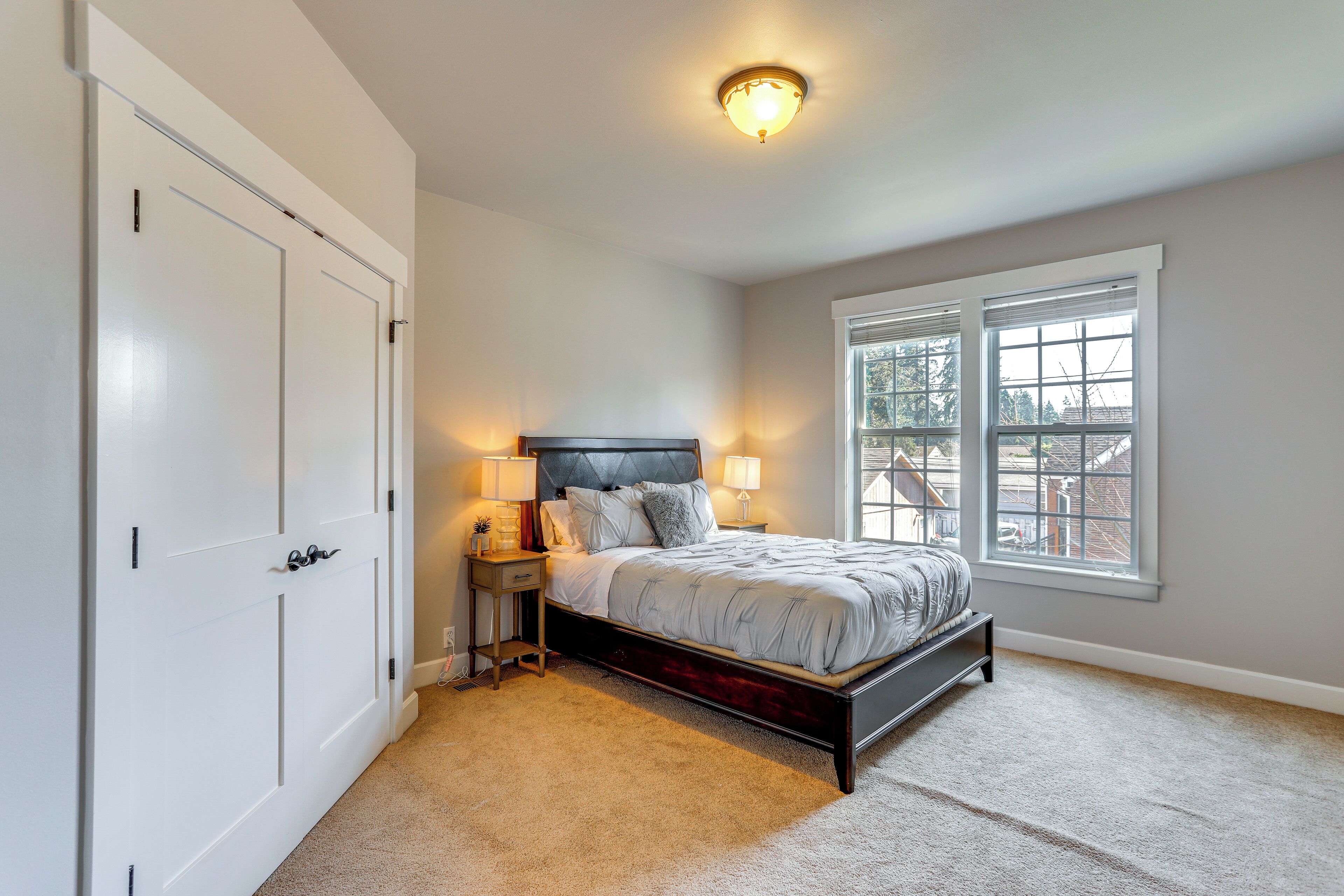 A bedroom with a bed, bedside lamps, a window, and a door.