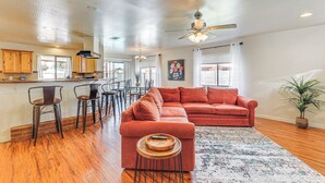 A spacious living area with a large sofa, wooden flooring, and a ceiling fan. - Private Pool & Patio: Home Near Mesa Arts Center! (Mesa)