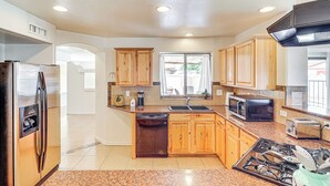 A kitchen with wooden cabinets, a stainless steel refrigerator, a dishwasher, a microwave, a sink, and a stove. - Private Pool & Patio: Home Near Mesa Arts Center! (Mesa)