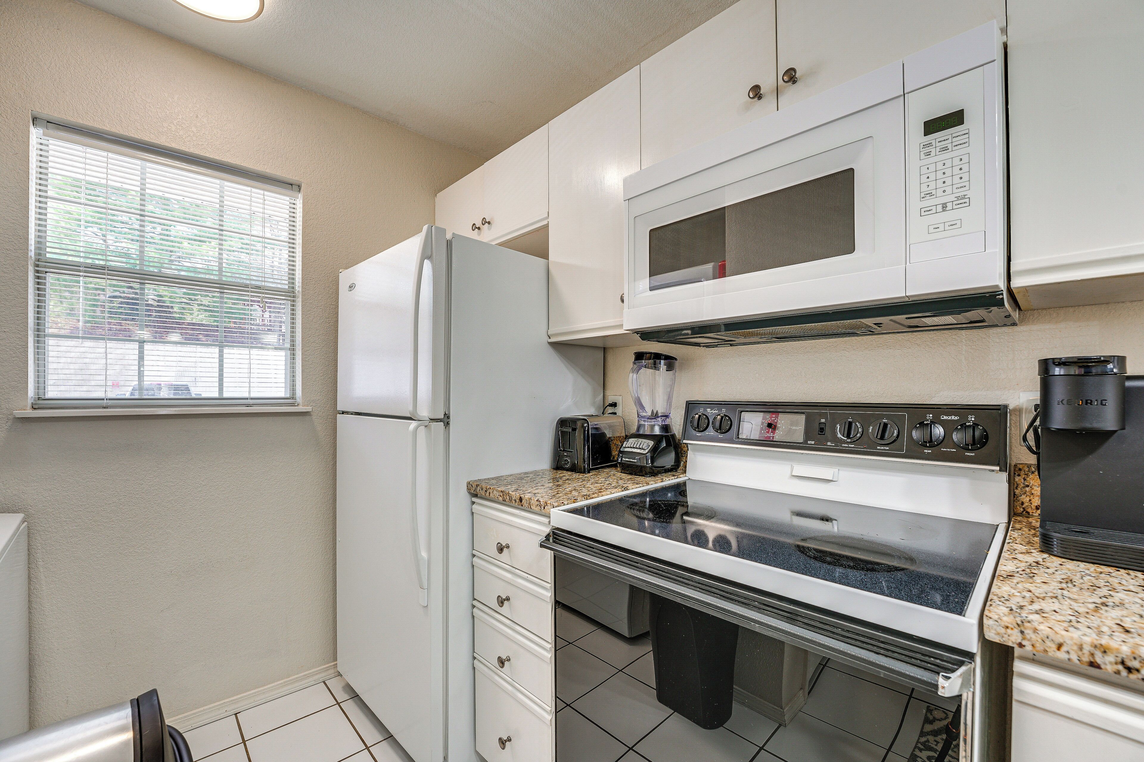 A compact kitchen with a refrigerator, microwave, stove, and toaster.