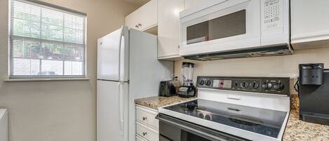 A compact kitchen with a refrigerator, microwave, stove, and toaster.