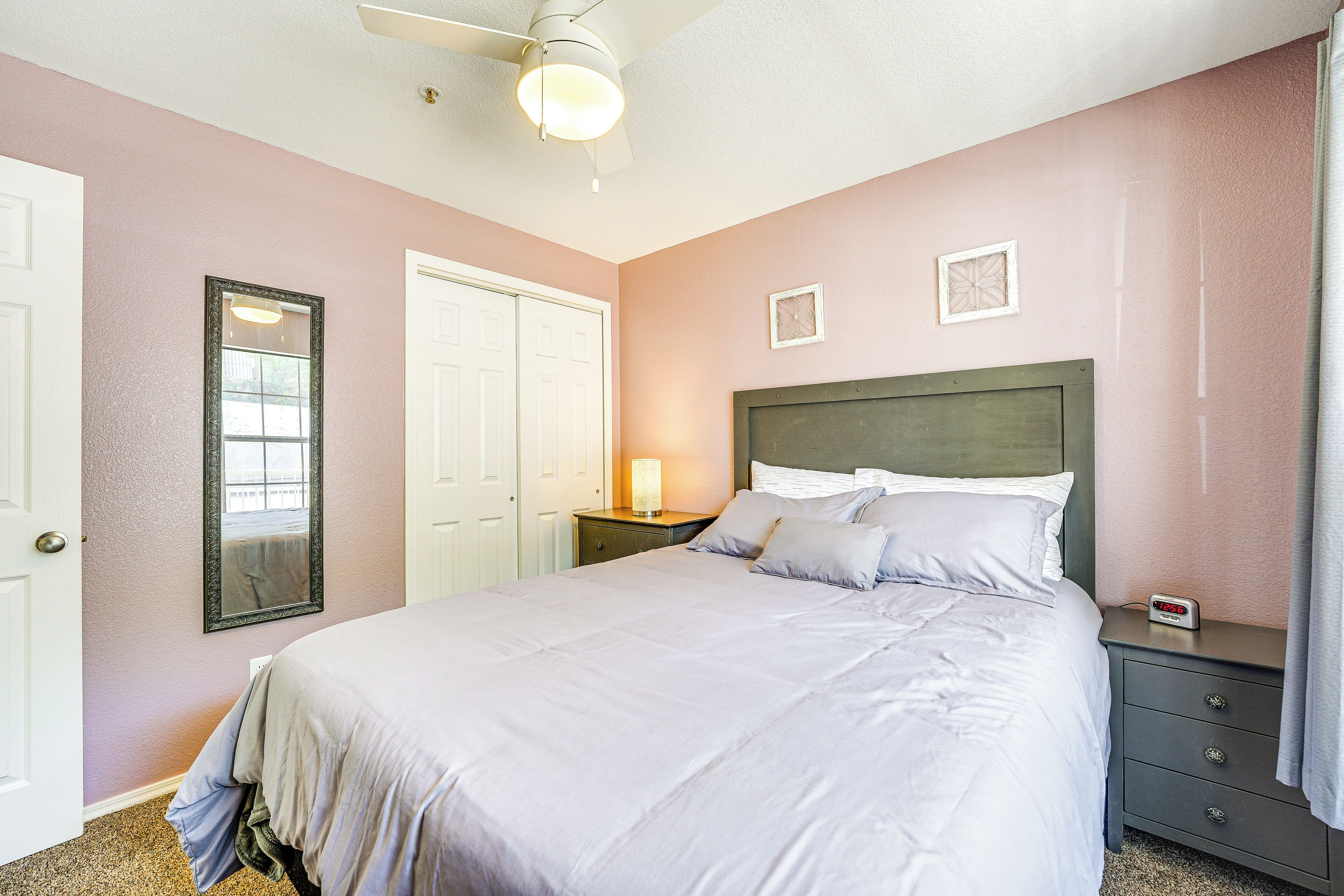 A bedroom with a bed, bedside table, nightstand, and a ceiling fan.