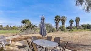 An outdoor patio with a round table and chairs, surrounded by palm trees and a fenced area. - Peaceful Riverside Home w/ Patio, 7 Mi to Downtown (Riverside)