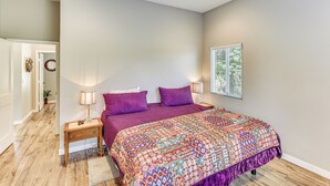 A bedroom with a large bed, two bedside tables with lamps, a wooden floor, and a window with blinds. - Peaceful Riverside Home w/ Patio, 7 Mi to Downtown (Riverside)