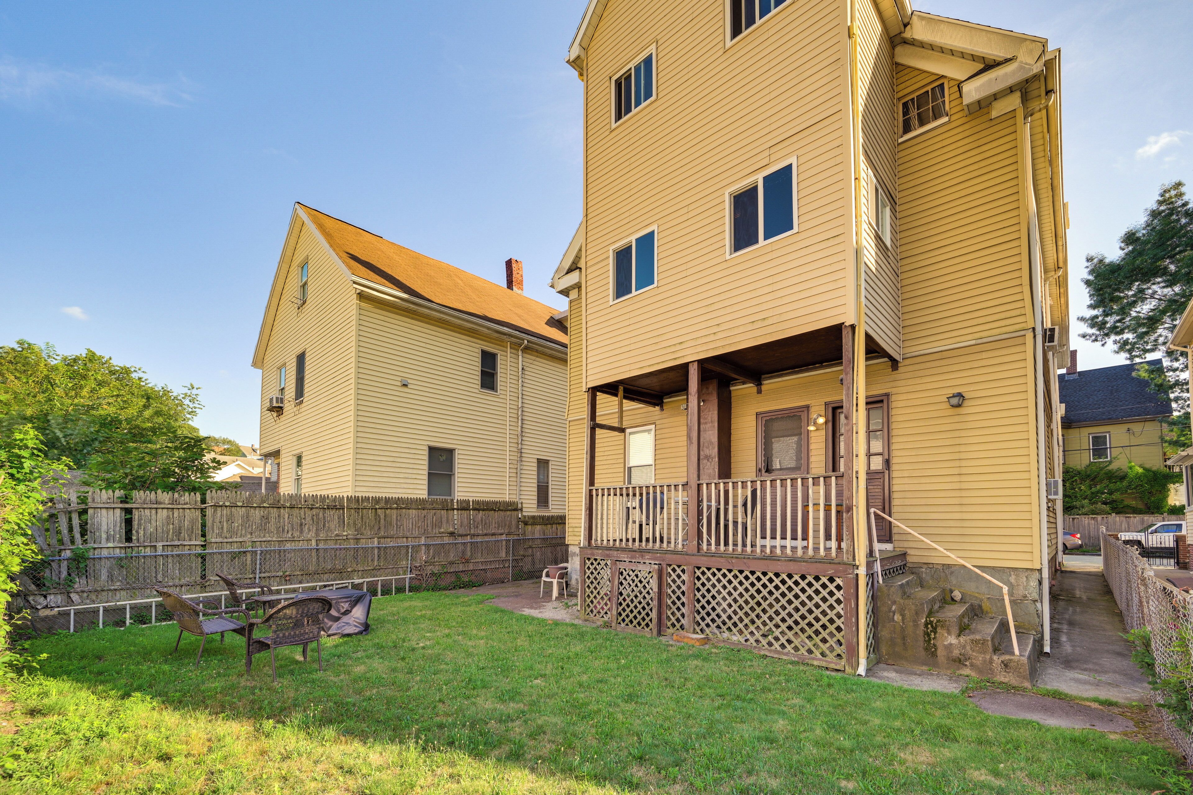 A two-story yellow house with a covered porch and a fenced backyard.