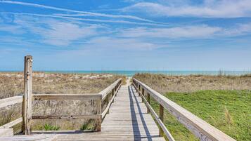 A wooden boardwalk leading to a beach with a clear sky.