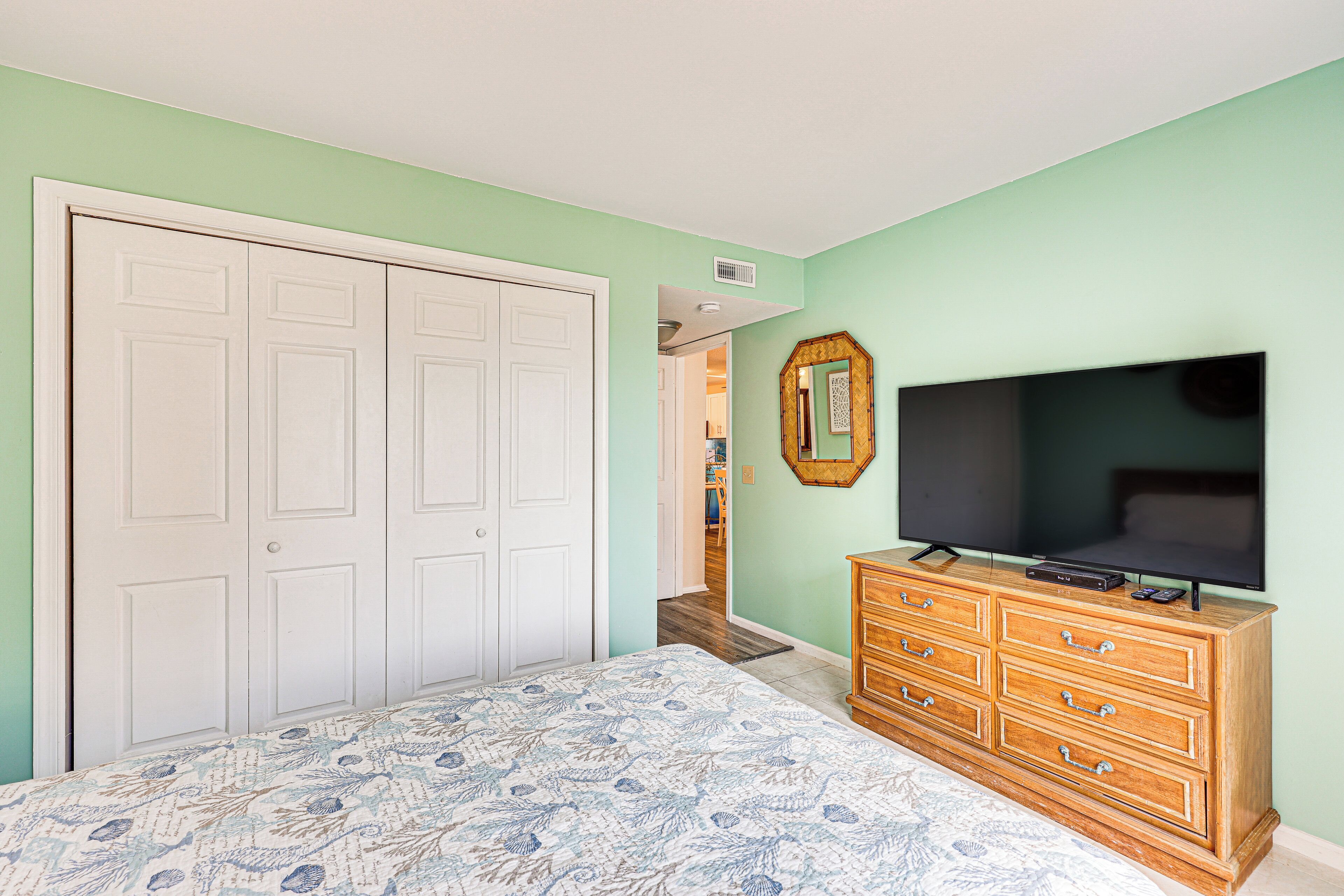 A bedroom with a bed, a dresser, a TV, and a closet.