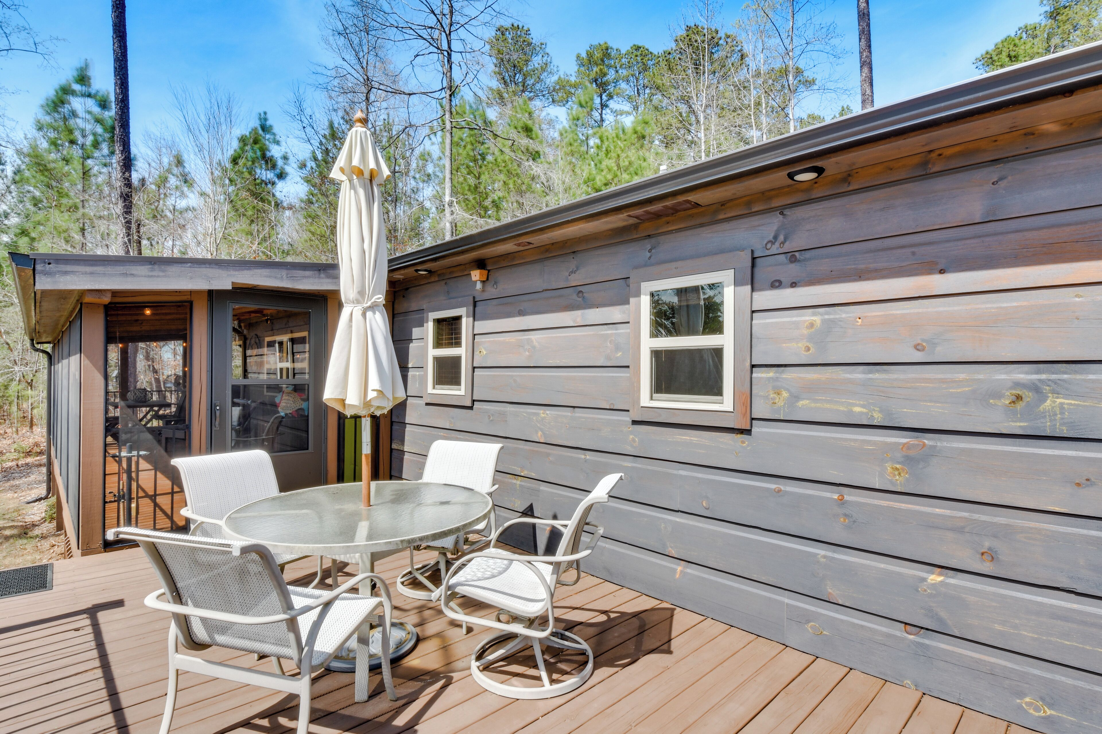 A wooden cabin with a deck, outdoor seating, and a glass door leading to an interior space.