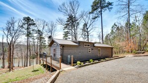 A cabin with a gravel driveway, a wooden deck, and a view of a lake surrounded by trees. - Waterfront Seneca Cabin ~ 4 Mi to Boat Launch! (Seneca)