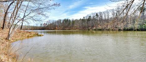A calm lake surrounded by leafless trees and a clear sky.
