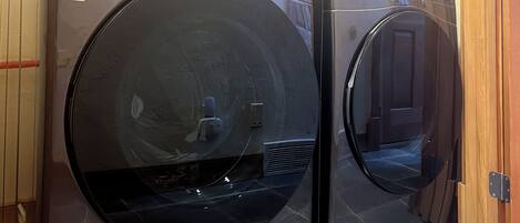 Two front-loading LG washing machines in a laundry room with tiled flooring and wooden walls.