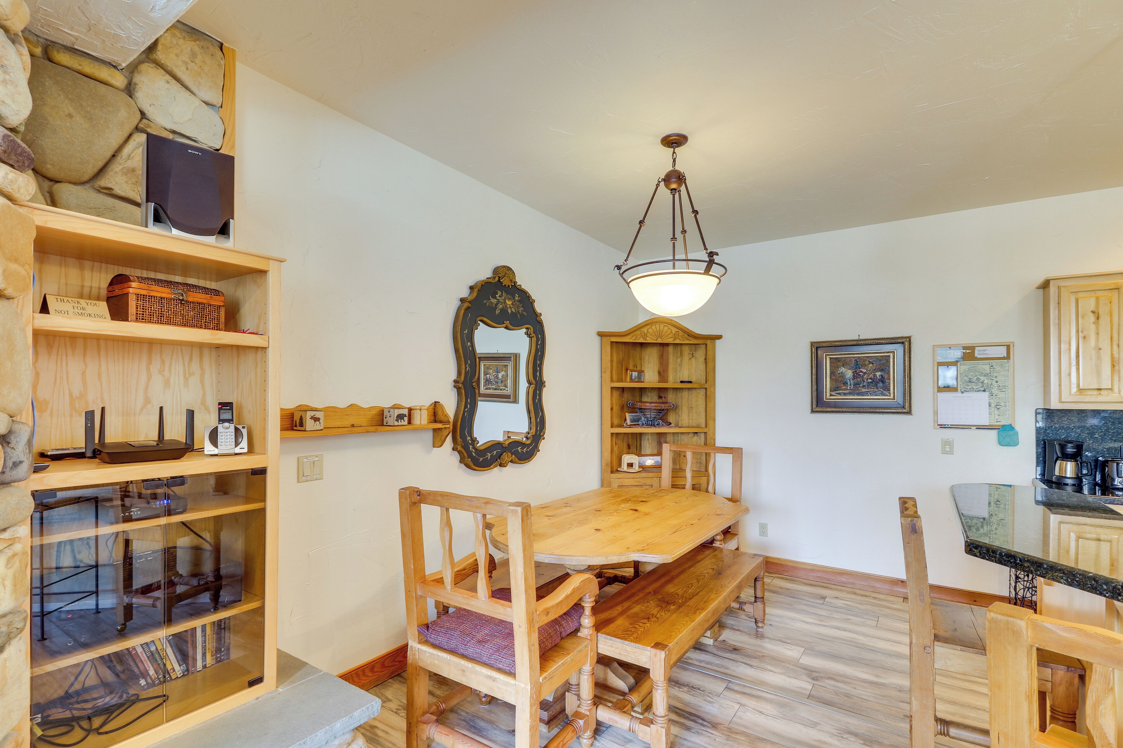 A wooden dining table with benches, surrounded by shelves with books and decorative items.