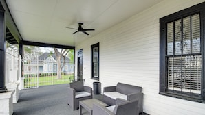 A covered porch with wicker furniture, a ceiling fan, and a view of a house in the background. - Stylish Home ~ 2 Mi to Jackson State & Belhaven! (Jackson)