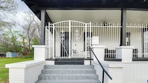 A covered porch with a white railing, a set of stairs leading up to the entrance, and a small shed in the background. - Stylish Home ~ 2 Mi to Jackson State & Belhaven! (Jackson)