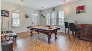 A pool table in a room with large windows, a door, and a bar area. - Stylish Home ~ 2 Mi to Jackson State & Belhaven! (Jackson)