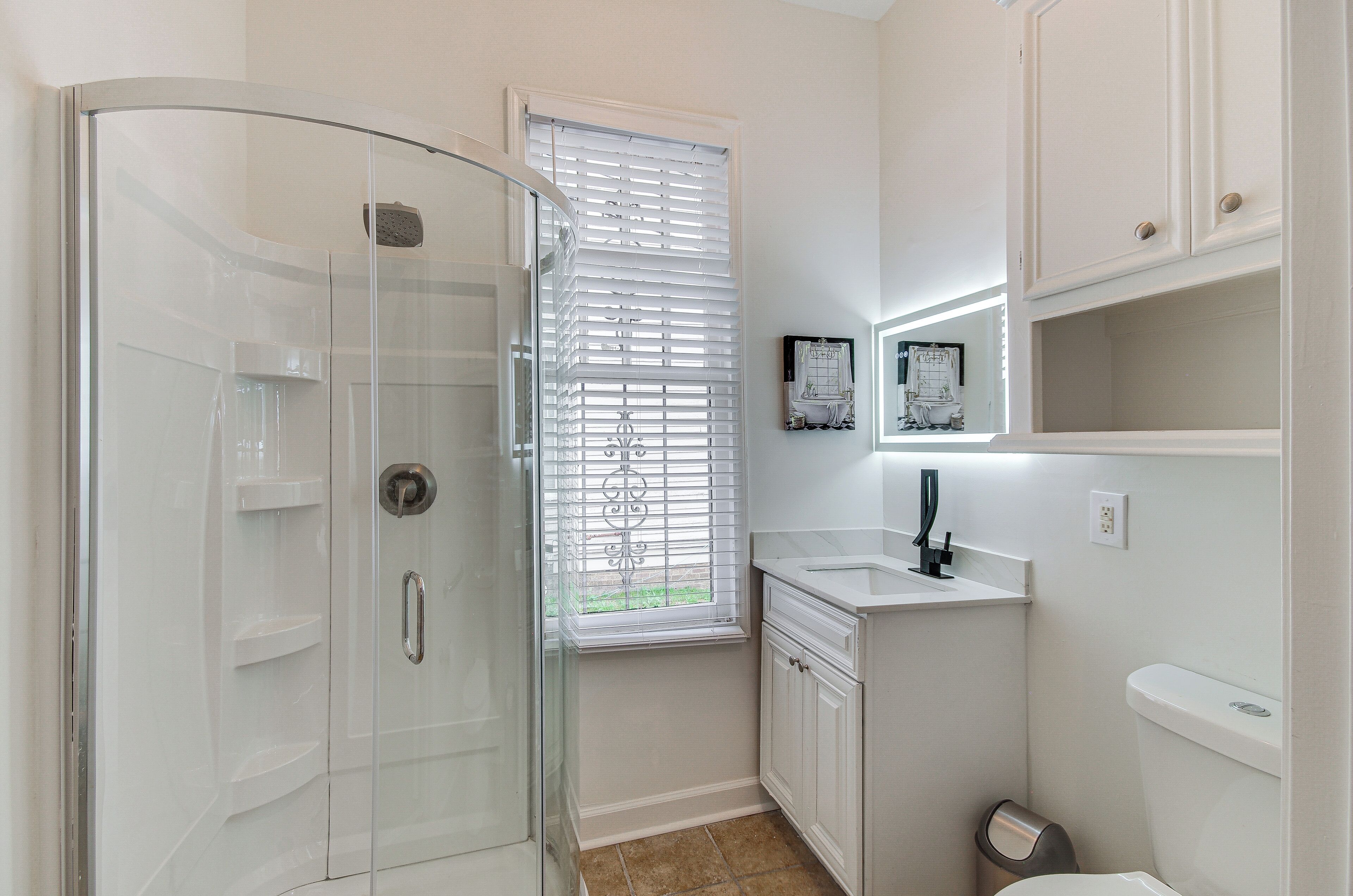 Un bagno moderno con box doccia in vetro, un lavandino con specchio sopra e un water.