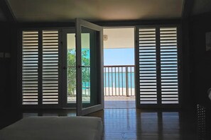 Quarto com uma grande porta de correr que dá para uma varanda com vista para o mar.