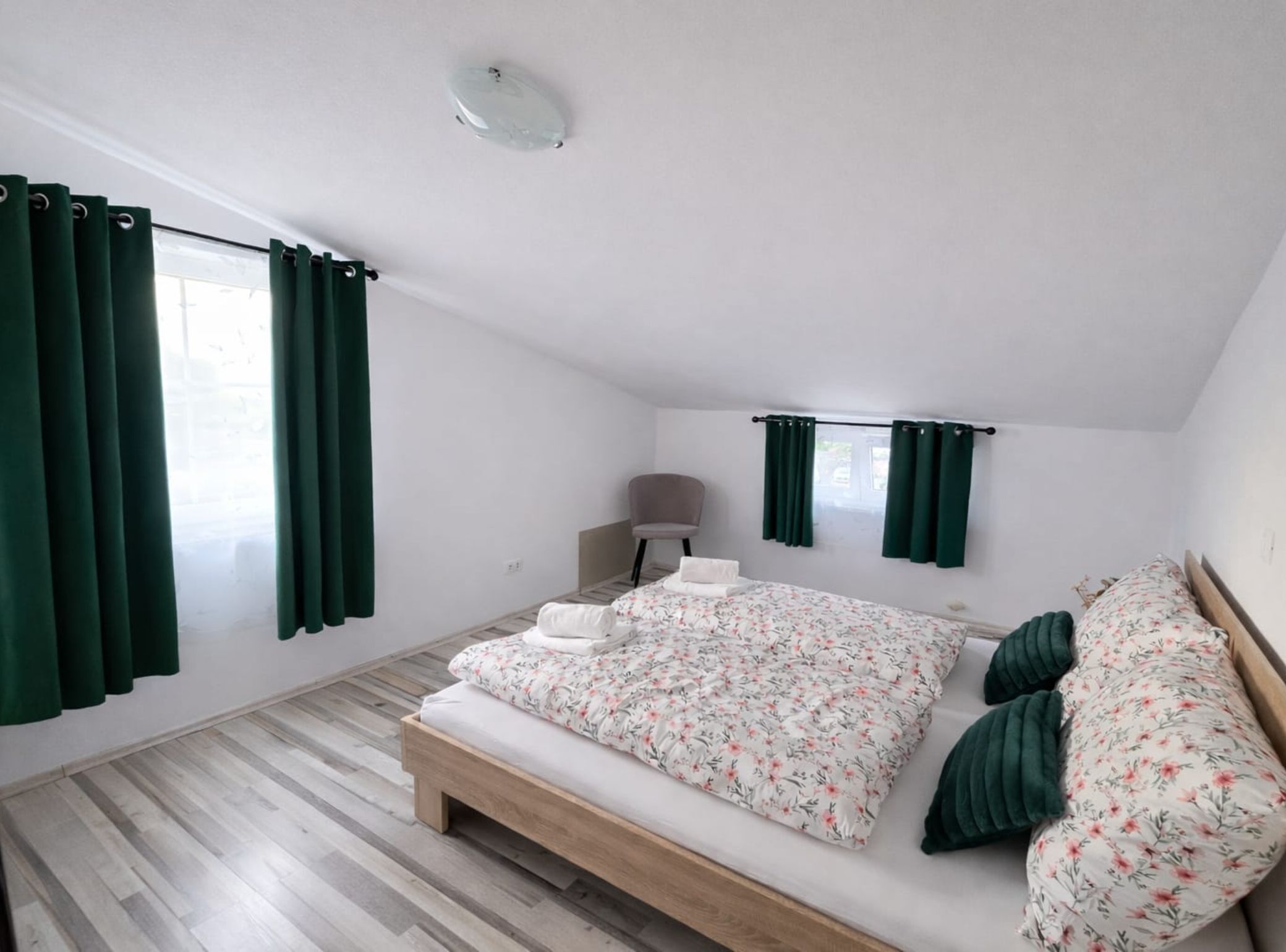 Une chambre à coucher avec un lit en bois, des rideaux verts, une table de chevet et une lampe.