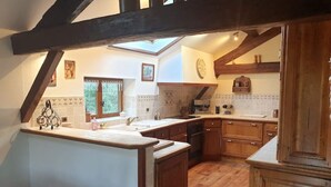Une cuisine avec des meubles en bois, un grand îlot central et une lucarne.