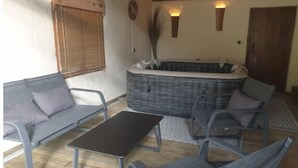Une pièce confortable avec un canapé, deux fauteuils, une petite table et un jacuzzi.