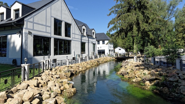 A modern building with large windows and a stone pathway leading to a water feature. - Domaine de Bracheux (Fouquenies)