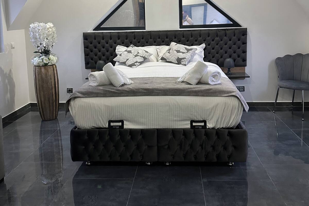 A modern bedroom with a large bed, a decorative vase, and a chair.