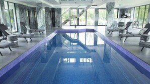 A large indoor swimming pool with a clear view of the surrounding area, including a staircase and seating area. - Domaine de Bracheux (Fouquenies)