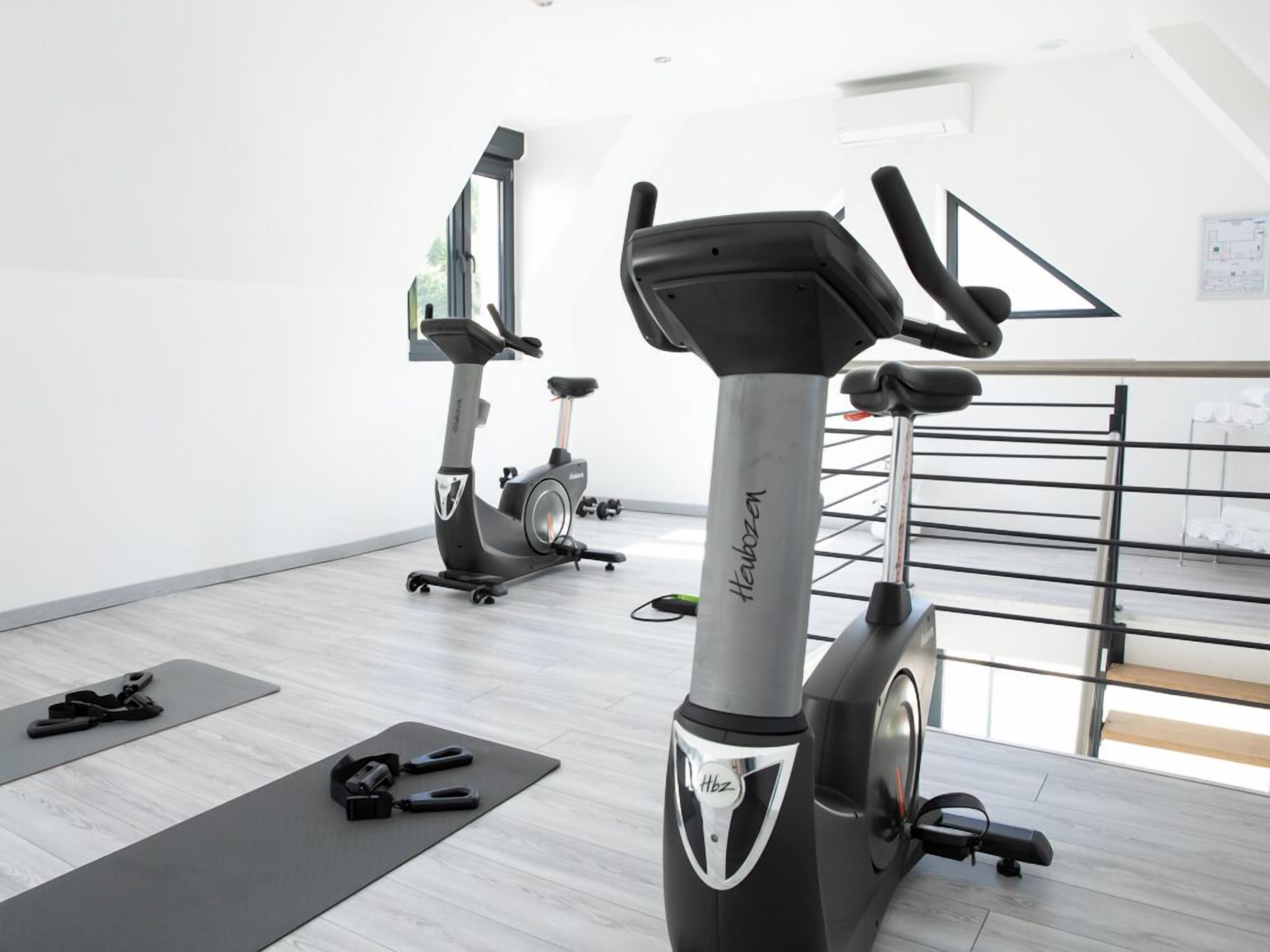 Un gimnasio con bicicletas estáticas, colchonetas de ejercicio y pesas.