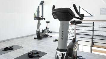 Un gimnasio con bicicletas estáticas, colchonetas de ejercicio y pesas.