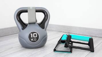 Una kettlebell gris con un asa e indicador de peso de 10 KG, y un soporte negro y turquesa para kettlebell.