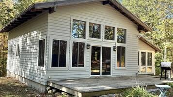 Une maison de plain-pied avec une terrasse à l’avant, de grandes fenêtres et une antenne parabolique.
