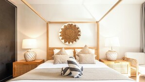 Habitación de hotel con una cama grande, dos mesitas de noche con lámparas, un adorno en la pared y una silla.